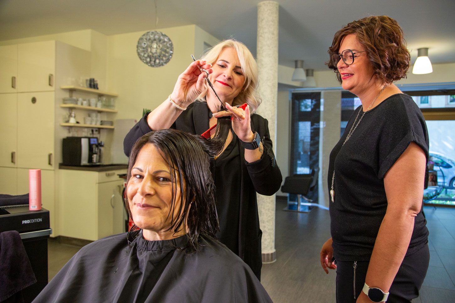 Inhaberin Nicole Jöst-Braun berät Master-Stylistin Andrea Berschet, die einer glücklichen Kundin die Haare schneidet