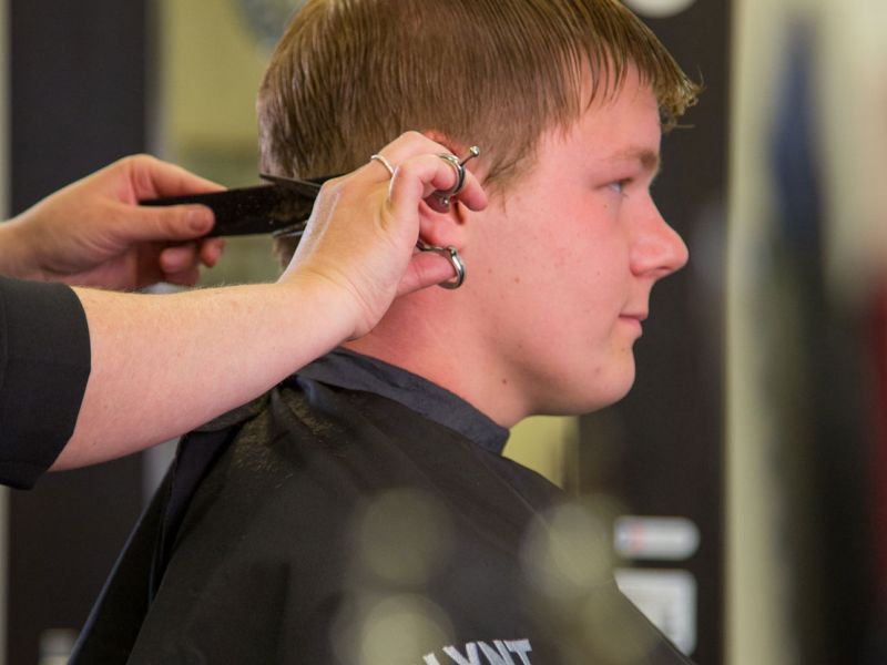 Ein junger Mann bekommt die Haare am Hinterkopf geschnitten