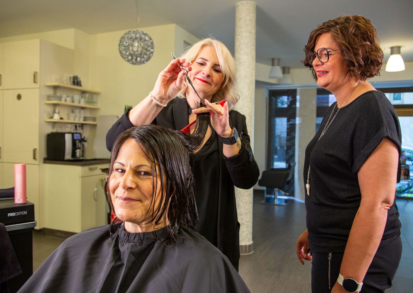 Inhaberin Nicole Jöst-Braun berät Master-Stylistin Andrea Berschet, die einer glücklichen Kundin die Haare schneidet