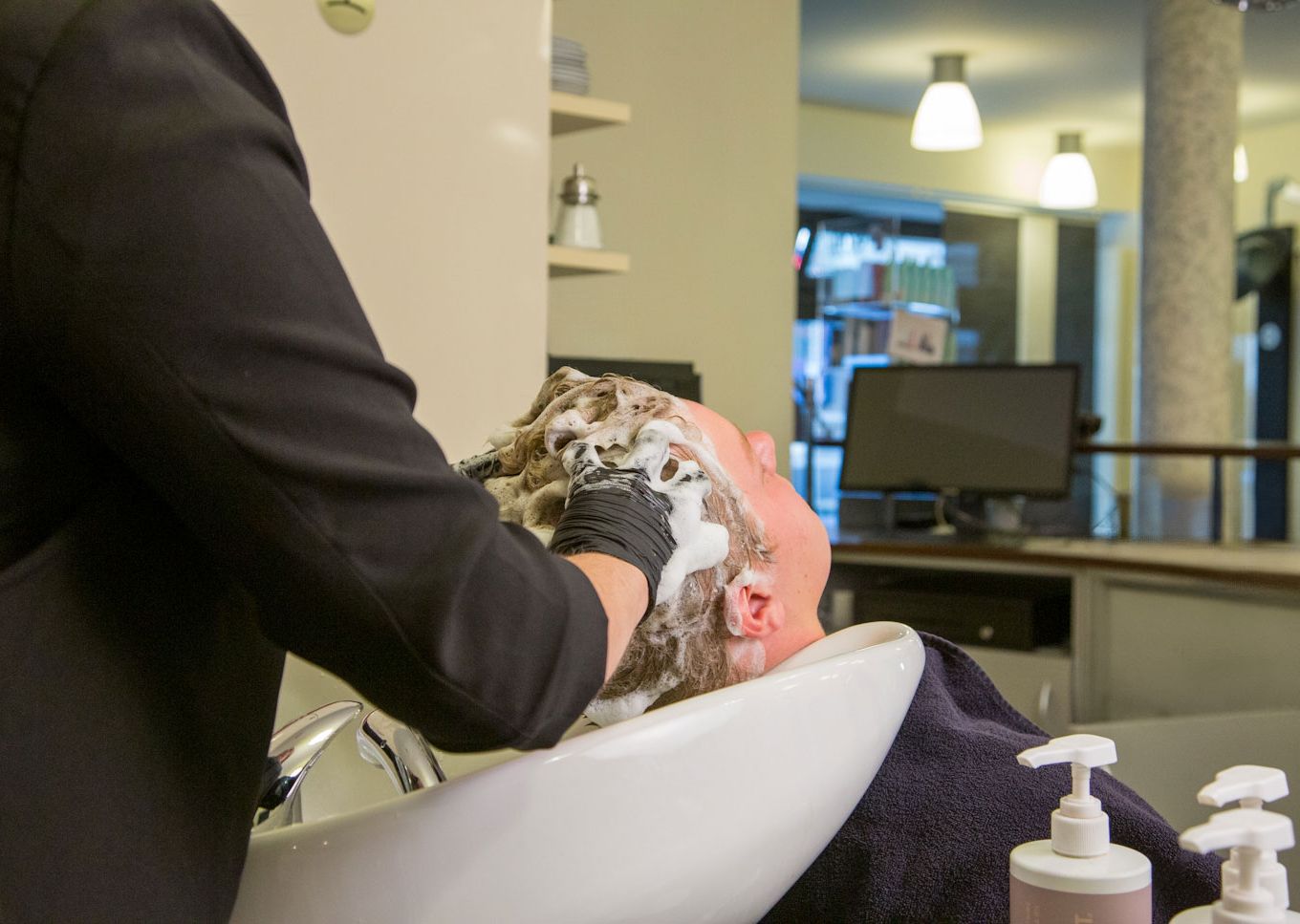 Detailaufnahme am Haarwaschbecken – die Haare eines Kunden werden eingeschäumt