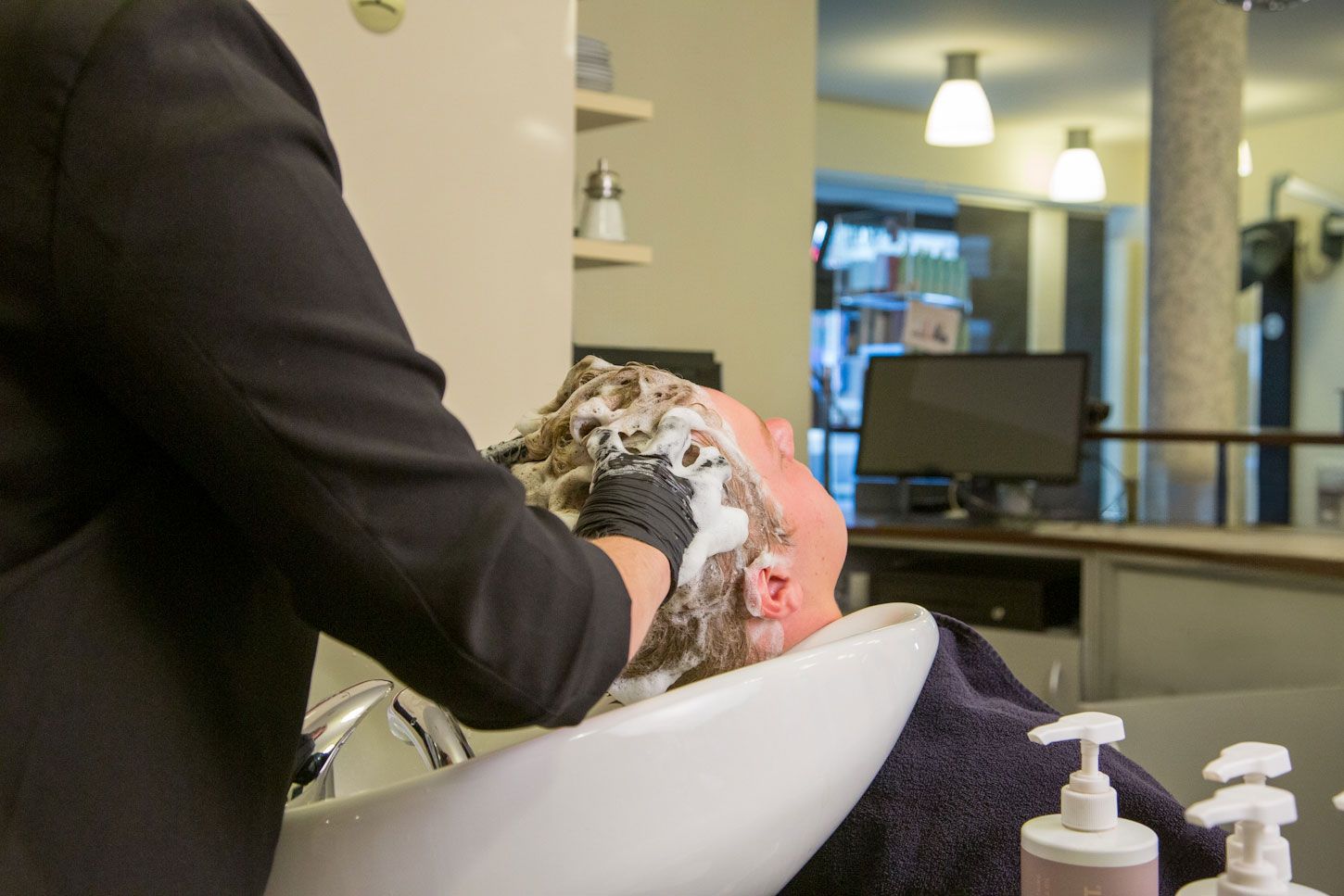 Die Haare eines Kunden werden eingeschäumt